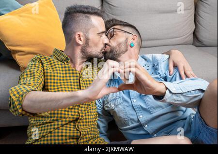 Junge Homosexuell Paar küssen während dabei Herz Symbol mit Händen zu Hause. Hochwertige Fotografie. Stockfoto