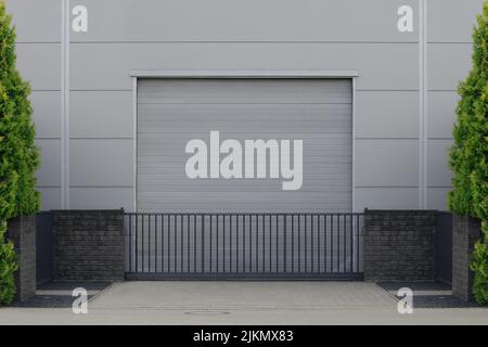 Rollentür oder Rollladen mit Anwendung in Fabrik, Lager oder Hangar. Draußen Bäume an den Seiten Stockfoto