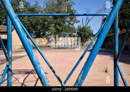 Leerer Basketballplatz, an einem sonnigen Tag von einer Schiene begrenzt Stockfoto