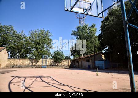 Leerer Basketballplatz, an einem sonnigen Tag von einer Schiene begrenzt Stockfoto