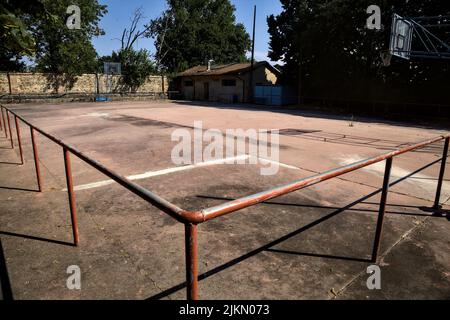 Leerer Basketballplatz, an einem sonnigen Tag von einer Schiene begrenzt Stockfoto