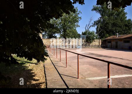 Leerer Basketballplatz, an einem sonnigen Tag von einer Schiene begrenzt Stockfoto