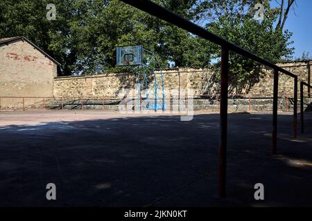 Leerer Basketballplatz, an einem sonnigen Tag von einer Schiene begrenzt Stockfoto