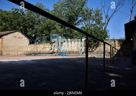 Leerer Basketballplatz, an einem sonnigen Tag von einer Schiene begrenzt Stockfoto