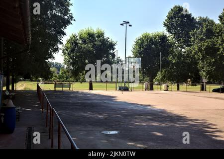 Leerer Basketballplatz, an einem sonnigen Tag von einer Schiene begrenzt Stockfoto