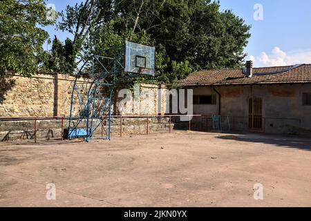 Leerer Basketballplatz, an einem sonnigen Tag von einer Schiene begrenzt Stockfoto