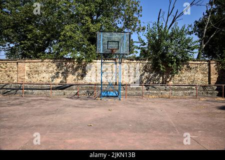 Leerer Basketballplatz, an einem sonnigen Tag von einer Schiene begrenzt Stockfoto