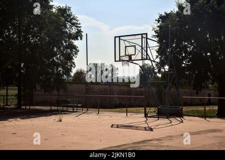 Leerer Basketballplatz, an einem sonnigen Tag von einer Schiene begrenzt Stockfoto