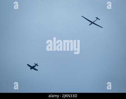 Die beiden Flugzeuge, die mit einem Seil verbunden sind, fliegen am blauen Himmel. Stockfoto