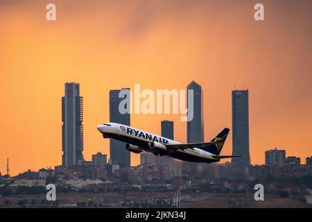 Madrid, Spanien. 02. August 2022. Ein Ryanair-Flugzeug, das während eines Sommersturms bei Sonnenuntergang vom Flughafen Adolfo Suarez Madrid Barajas abfliegt, kommt an den Wolkenkratzern des Geschäftsviertels Four Towers vorbei. Regen und Hagel haben die Stadt Madrid während eines Sommersturms erreicht, begleitet von hohen Temperaturen während einer Hitzewelle, bei der in einigen Gebieten der Gemeinde Madrid tagsüber 40 Grad Celsius überschritten wurden. Quelle: Marcos del Mazo/Alamy Live News Stockfoto