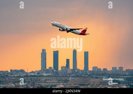 Madrid, Spanien. 02. August 2022. Ein Iberia-Flugzeug, das während eines Sommersturms bei Sonnenuntergang vom Flughafen Adolfo Suarez Madrid Barajas abfliegt, kommt an den Wolkenkratzern des Geschäftsviertels Four Towers vorbei. Regen und Hagel haben die Stadt Madrid während eines Sommersturms erreicht, begleitet von hohen Temperaturen während einer Hitzewelle, bei der in einigen Gebieten der Gemeinde Madrid tagsüber 40 Grad Celsius überschritten wurden. Quelle: Marcos del Mazo/Alamy Live News Stockfoto