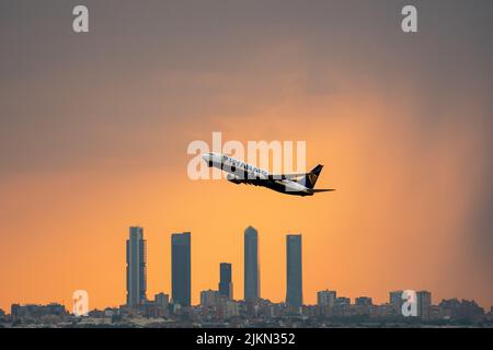 Madrid, Spanien. 02. August 2022. Ein Ryanair-Flugzeug, das während eines Sommersturms bei Sonnenuntergang vom Flughafen Adolfo Suarez Madrid Barajas abfliegt, kommt an den Wolkenkratzern des Geschäftsviertels Four Towers vorbei. Regen und Hagel haben die Stadt Madrid während eines Sommersturms erreicht, begleitet von hohen Temperaturen während einer Hitzewelle, bei der in einigen Gebieten der Gemeinde Madrid tagsüber 40 Grad Celsius überschritten wurden. Quelle: Marcos del Mazo/Alamy Live News Stockfoto