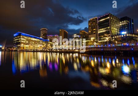 Eine wunderschöne Nachtansicht der Architektur von Manchester, die sich im Wasser widerspiegelt Stockfoto