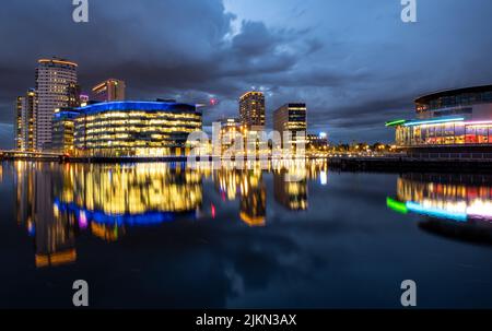 Eine wunderschöne Nachtansicht der Architektur von Manchester, die sich im Wasser widerspiegelt Stockfoto