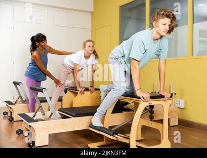 Kleiner Junge und Mädchen mit Pilates-Trainer im Fitnessstudio Stockfoto