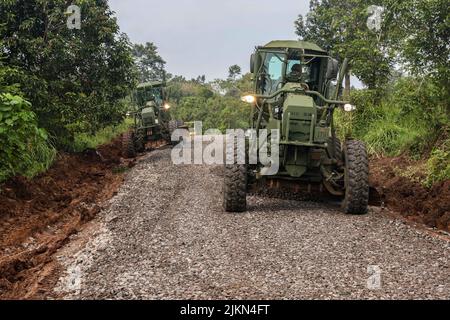 Lote der 130. Engineer Brigade, 84. Engineer Bataillon streut bei gemeinsamen Straßenreparaturarbeiten im Python 1 Range, Baturaja, Indonesien, 31. Juli 2022, Schotter mit einem 120m Motor Grader aus Als Teil von Garuda Shield 2022. Garuda Shield, ein Teil der Operation Pathways und eine langjährige jährliche, bilaterale Militärübung zwischen dem US-Militär und den nationalen Streitkräften Indonesiens, verstärkt die Verpflichtungen der USA gegenüber unseren Verbündeten und regionalen Partnern, die gemeinsame Bereitschaft und die Interoperabilität, gemeinsam zu kämpfen und zu gewinnen. (USA Armeefoto von Sgt. Kyler Chatman, 8. Theatre Sustainment Stockfoto