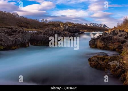 Eine wunderschöne Landschaft des Bruarfoss Wasserfalls auf Felsen vor einem blau bewölkten Himmel in Brekkuskogur, Island Stockfoto