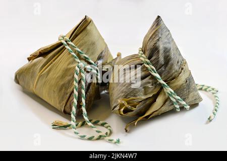 Chinesische klebrige Reisknödel, Zongzi oder Baccang, aus klejeweigem Reis, gefüllt mit verschiedenen Füllungen, eingewickelt in Bambusblätter Stockfoto