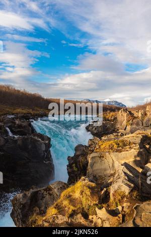 Eine wunderschöne Landschaft des Bruarfoss Wasserfalls auf Felsen vor einem blau bewölkten Himmel in Brekkuskogur, Island Stockfoto