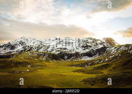 Eine schöne Landschaftsansicht von verschneiten Bergen auf Grasland mit einem bewölkten Himmel in Rangarping, Eystra Southern, Island Stockfoto