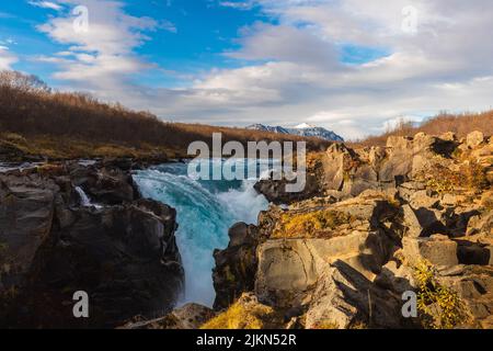 Eine wunderschöne Landschaft des Bruarfoss Wasserfalls auf Felsen vor einem blau bewölkten Himmel in Brekkuskogur, Island Stockfoto