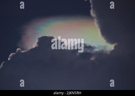 Eine Nahaufnahme großer Wolken am Himmel mit Regenbogen von hinten Stockfoto