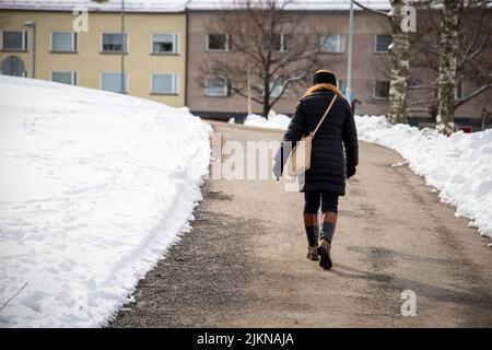 Eine Frau, die in einem verschneiten Winter auf der Straße läuft Stockfoto