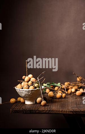 Eine selektive Aufnahme von frischen Longan-Früchten in einem Korb auf einem Holztisch Stockfoto