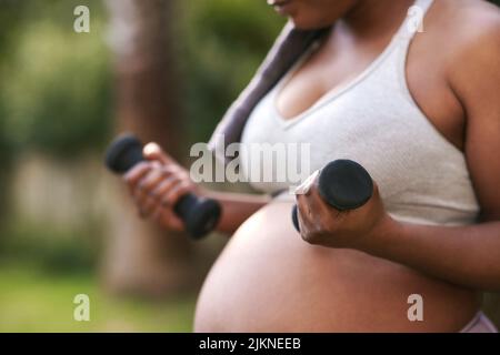 Du musst stark bleiben, Mama. Eine Schwangerin arbeitet mit Kurzhanteln. Stockfoto