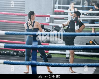 Fit, gesund und aktiv Frau tut Kick-Boxen Training im Fitnessstudio Sparring mit ihrem Personal Trainer in einem Wellness-Center lernen zu kämpfen. Sportlich Stockfoto