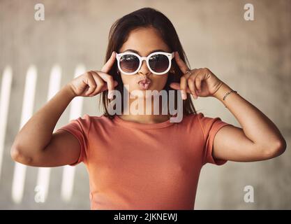Die Stadt gehört mir, sie verdankt mir einen Lebensunterhalt. Porträt einer attraktiven jungen Frau mit Sonnenbrillen vor städtischem Hintergrund. Stockfoto
