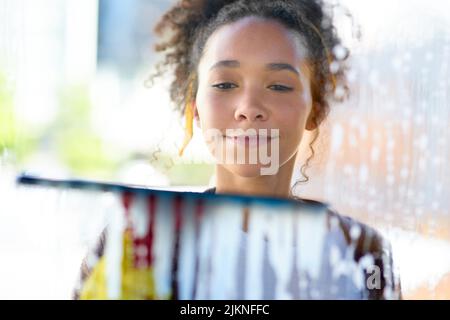 Wenn Sie Ihre Reflexion sehen können, dann ist es sauber. Eine junge Frau, die zu Hause die Fenster wascht. Stockfoto