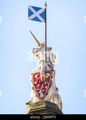 Auf dem Mercat Cross in Edinburgh, Lothian, Schottland, liegt eine Statue eines Einhorns mit einer schottischen Flagge und dem Royal Arms of Scotland. Stockfoto