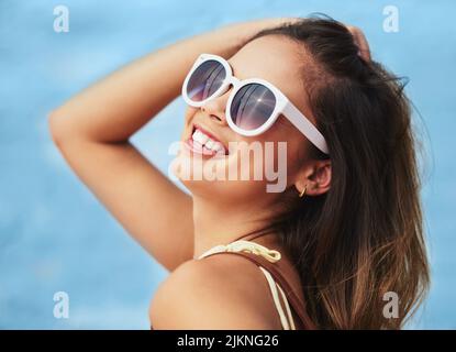 Nah, die Sommer warteten auf mich. Das verkürzte Porträt einer attraktiven jungen Frau, die ihre Sommertöne draußen vor einem blauen Hintergrund trägt. Stockfoto