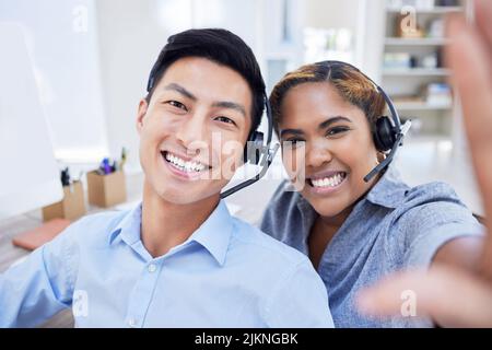 Selfie von verschiedenen Callcenter-Agenten oder Kollegen, die gemeinsam im Büro Spaß haben. Männliche und weibliche Kundendienstmitarbeiter machen ein Foto oder ein Stockfoto
