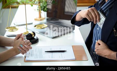 Ein Geschäftsmann, der seinem Anwalt Tribut zollt, bietet seinem Privatanwalt im Büro eine illegale Zahlung an. Korruptionskonzept. Zugeschnittenes Bild Stockfoto