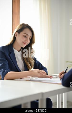 Porträt, attraktive junge Geschäftsfrau oder Geschäftsführerin, die mit ihrem Partner im Büro einen Geschäftsvertrag bespricht. Stockfoto