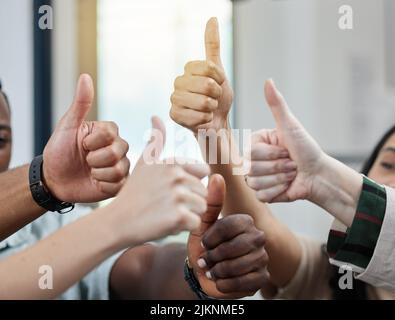 Mit einem Support-Team hinter Ihnen können Sie alles erreichen. Nahaufnahme einer Gruppe von nicht erkennbaren Geschäftsleuten, die den Daumen nach oben zeigen. Stockfoto