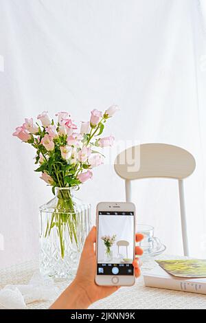 Eine vertikale Aufnahme einer Frau, die den Strauß von Kunden fotografiert Stockfoto