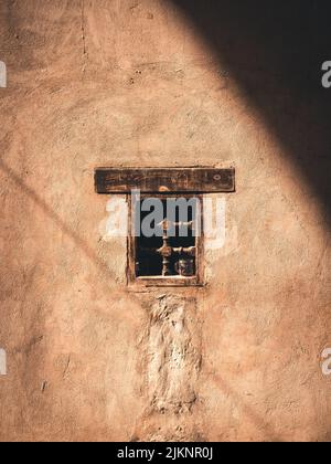 Eine schöne Aufnahme einer kleinen alten Witwe auf einer alten Steinmauer mit Sonnenlicht und Schatten in Assuan, Ägypten Stockfoto