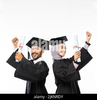 Selbstbewusste Absolventen tragen Togas mit Zertifikat, während sie das Stehen feiern Stockfoto