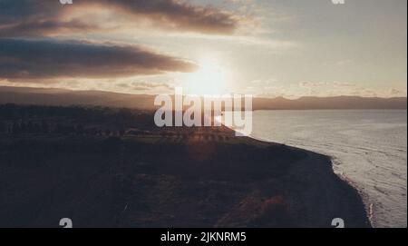 Die Sonne scheint hinter dunklen Wolken auf den Küstenfeldern Stockfoto