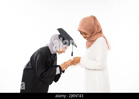 Asiatische weibliche Graduiertenschülerin trägt Toga schüttelt die Hände mit Mutter Stockfoto