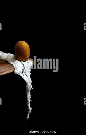 Eine vertikale Nahaufnahme der Kiwifruit am Rand des Tisches auf dunklem Hintergrund. Stillleben. Stockfoto