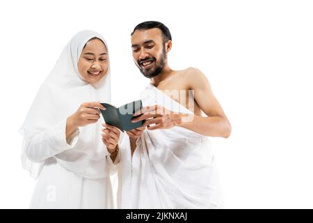 Fröhlicher Mann und Frau in ihram-Kleidung beim Lesen eines Passes Stockfoto