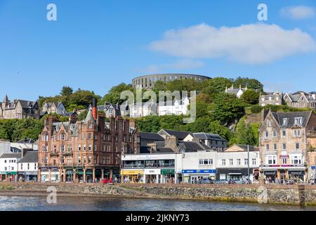 Oban Stadtzentrum und am Wasser Immobilien mit McCaig's Folly Turm auf dem Hügel, Westküste von Schottland, Großbritannien, Europa an blauem Himmel Sommer Tag 2022 Stockfoto