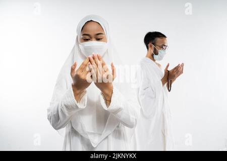 Frau in ihram-Kleidung und Maske, die al fatihah Gebet durchführt Stockfoto