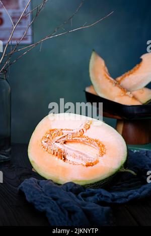 Eine vertikale Aufnahme einer halben Melone auf dem Tisch mit unscharfem Hintergrund von Melonen in Scheiben Stockfoto