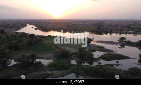 Ein Fluss fließt in die Ebene mit Sonnenuntergang im Hintergrund Stockfoto