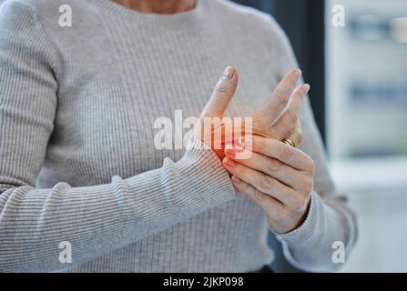 Es könnte Zeit sein, eine Karriere zu tauschen. Eine unkenntliche Geschäftsfrau, die allein in ihrem Büro steht und unter Karpaltunnel leidet. Stockfoto